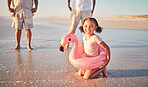 Beach, flamingo ring and child portrait on holiday with family in Mexico enjoying summer break. Young, happy and excited girl relaxing on ocean holiday sand for leisure fun with cheerful smile.