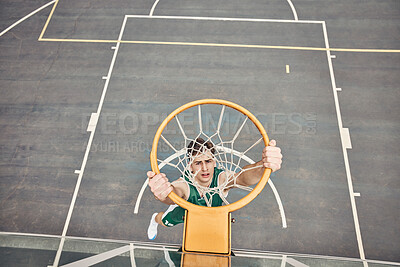 Buy stock photo Portrait of basketball player hanging on net on a basketball court. Young man playing basketball outside doing slam dunk and jumping to score a point. Motivation to win and have fun in sports game