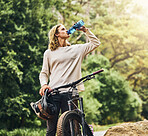 Mountain bike, drinking water and man from Berlin in nature after a adventure sport workout. Sports, exercise and fitness ride of a healthy person athlete training cardio on a outdoor road by trees