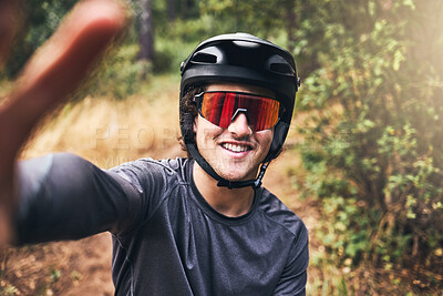 Buy stock photo Man taking a selfie while cycling on a nature trail, wearing a helmet and sunglasses. Portrait of a cyclist on bicycle ride through a park or forest taking a picture smiling and wearing safety gear