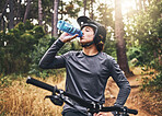 Mountain bike man drinking water bottle in forest, woods and mountains in healthy training, cycling freedom and sports challenge in Norway. Tired bicycle athlete relax for energy in adventure workout