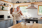 Dance, couple and kitchen with a senior man and woman dancing together in their home. Love, freedom and romance with an elderly male and female pensioner having fun in a house in the morning