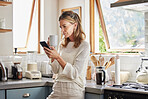 Coffee, phone and senior woman in kitchen browsing social media, text message or online app at home. Relax, tea and reading news or mobile online web surfing with female from Canada on 5g smartphone
