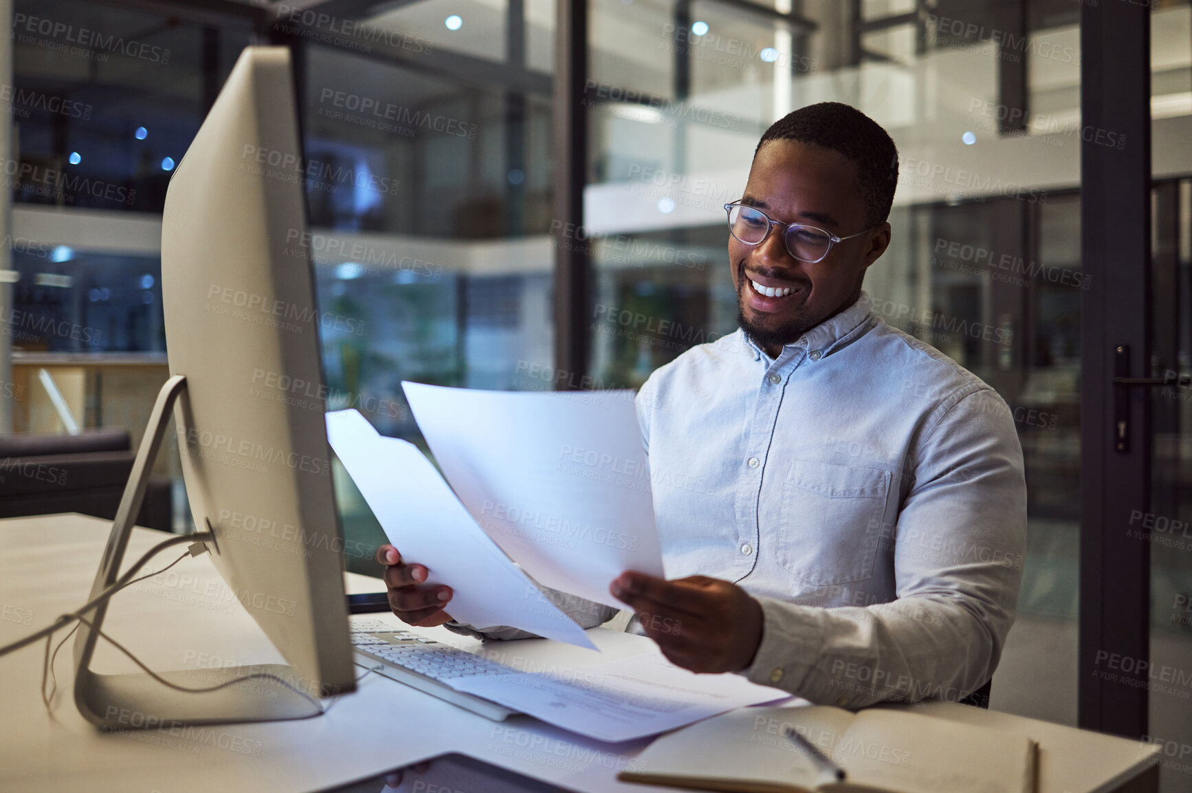 Buy stock photo Documents, night and computer with a businessman working at his desk late in the office. Paperwork, finance and tax with a male employee at work for overtime on a deadline while reading a report