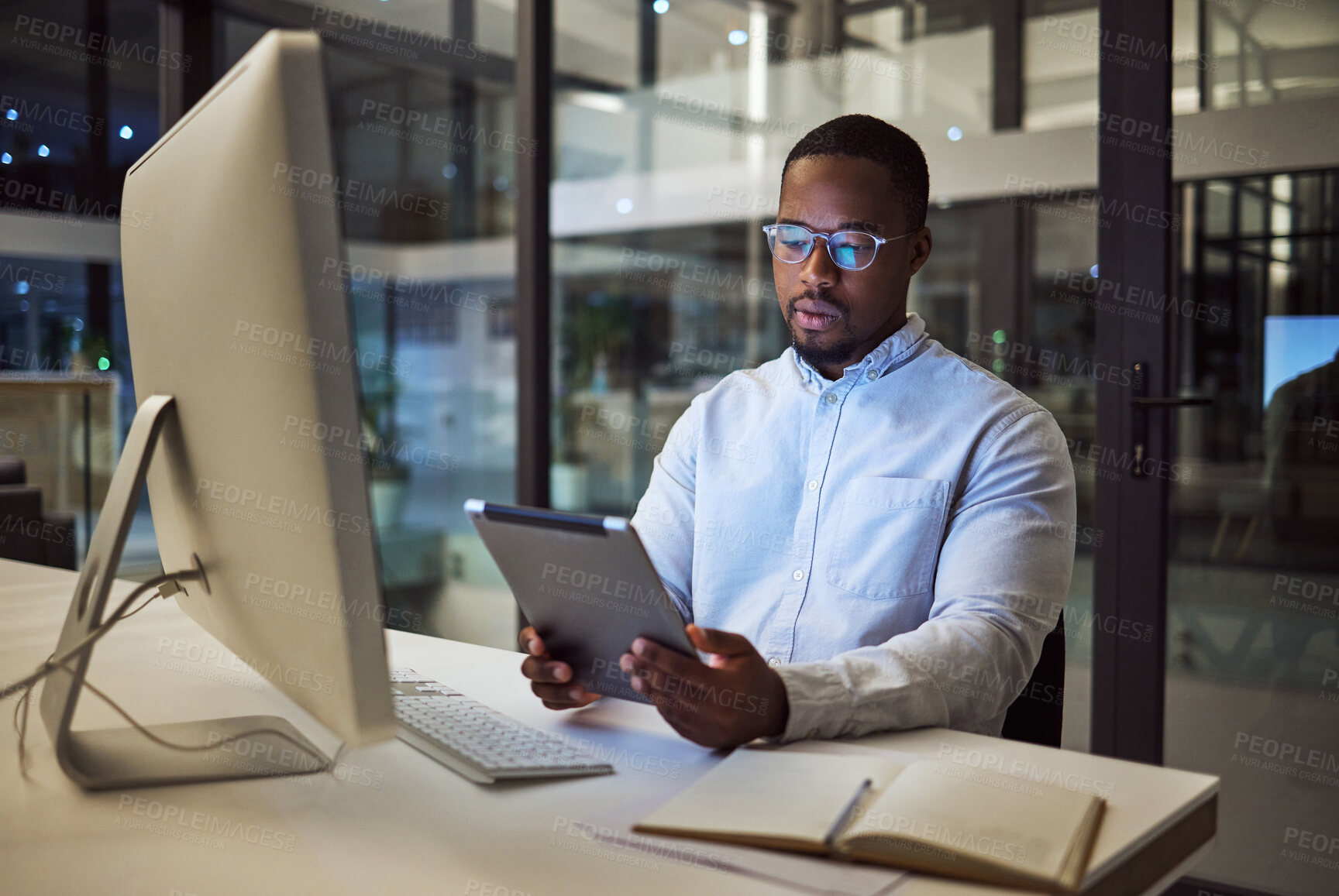 Buy stock photo Black businessman, tablet planning and desktop at night in startup for online ideas, strategy and connect apps on 5g technology in Nigeria. Employee working in dark modern office for internet project