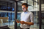 Businessman working on tablet at night for digital marketing online report at the office. Manager or employee reading communication on internet about tech proposal while working late at a startup job