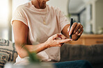 Healthcare, diabetes and a senior woman using blood sugar test on finger in living room. Health, innovation and daily life of diabetic lady on sofa with glucometer to check glucose level in her home.