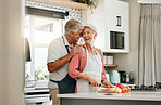 Senior couple in kitchen, cooking healthy food together and happy in retirement lifestyle. Elderly woman chopping vegetables with apron, old white man hug wife in home and love nutrition dinner meal