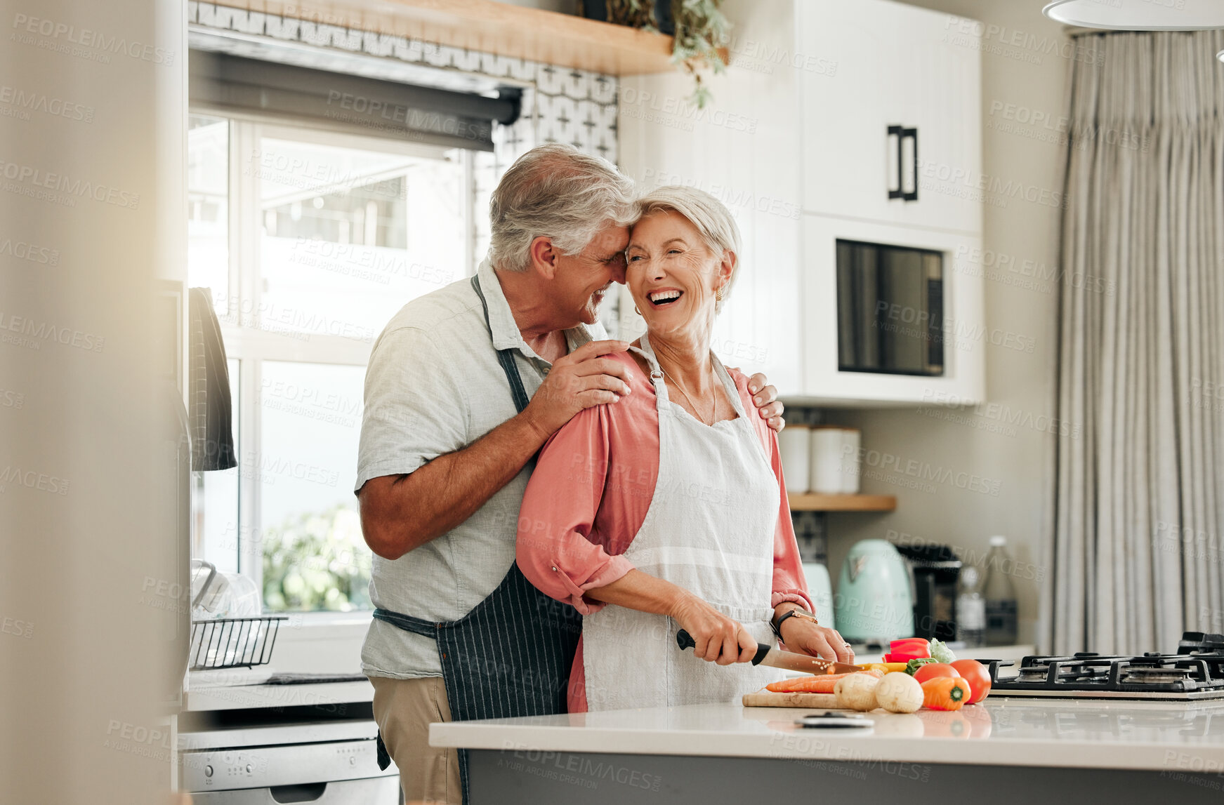 Buy stock photo Senior couple in kitchen, cooking healthy food together and happy in retirement lifestyle. Elderly woman chopping vegetables with apron, old white man hug wife in home and love nutrition dinner meal