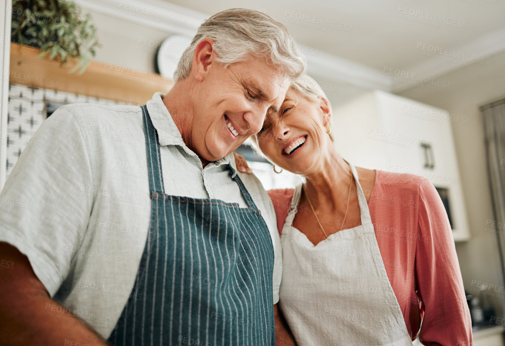 Buy stock photo Senior couple, love and cooking while wearing an apron, laughing and happy bonding together in their home kitchen and enjoying healthy relationship. Old man and woman enjoying retirement with a smile