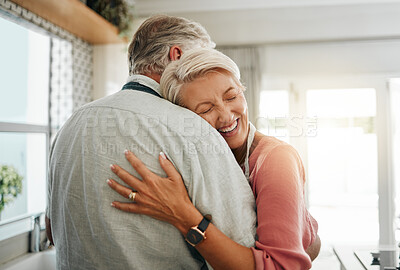 Buy stock photo Hug, love and safe with a senior couple hugging or embracing in the kitchen of their home together. Happy, smile and affection with an elderly male and female pensioner sharing a warm embrace