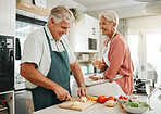 A happy senior couple, cooking healthy food in kitchen and drinking champaign as they enjoy retirement. Elderly woman with sitting on counter, man with silver laughing and they smile in love together