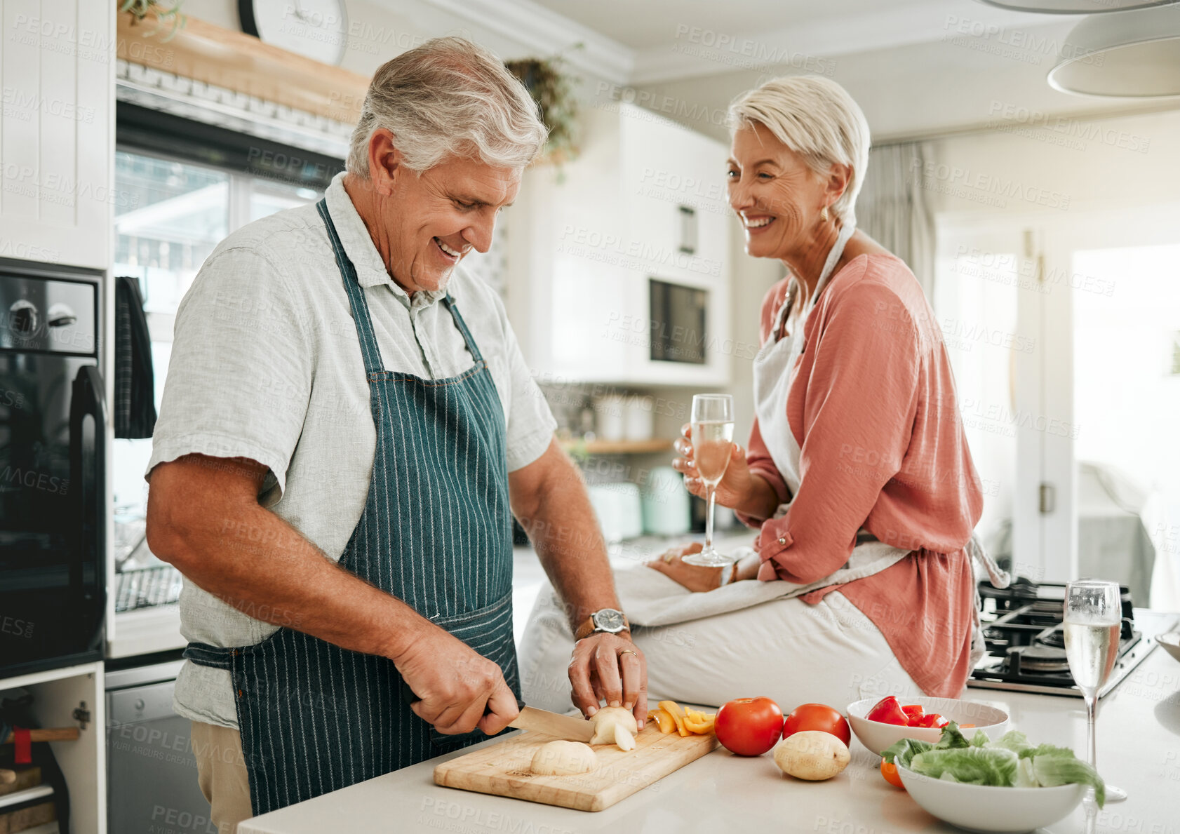 Buy stock photo A happy senior couple, cooking healthy food in kitchen and drinking champaign as they enjoy retirement. Elderly woman with sitting on counter, man with silver laughing and they smile in love together