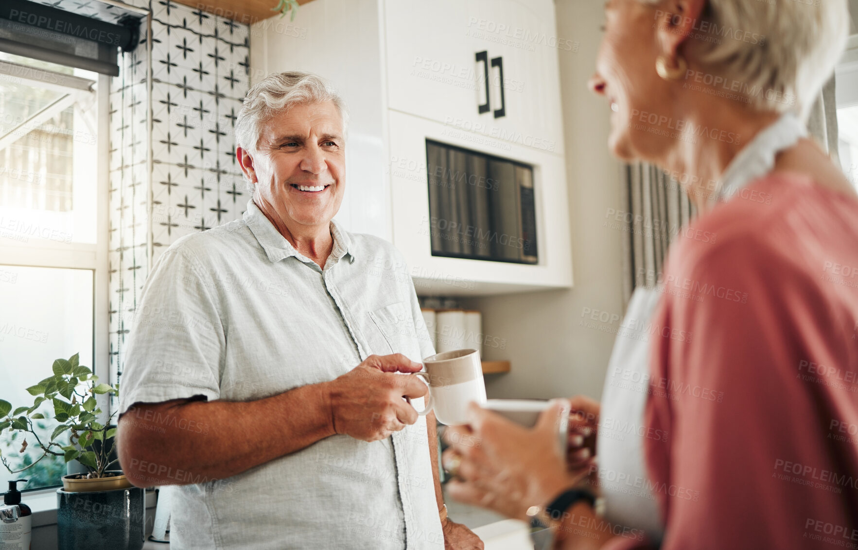 Buy stock photo Senior man, drinking coffee and conversation with woman in kitchen at home in New Zealand. Happy, elderly and smile couple enjoy morning tea, chat and relax together in apartment for retirement break