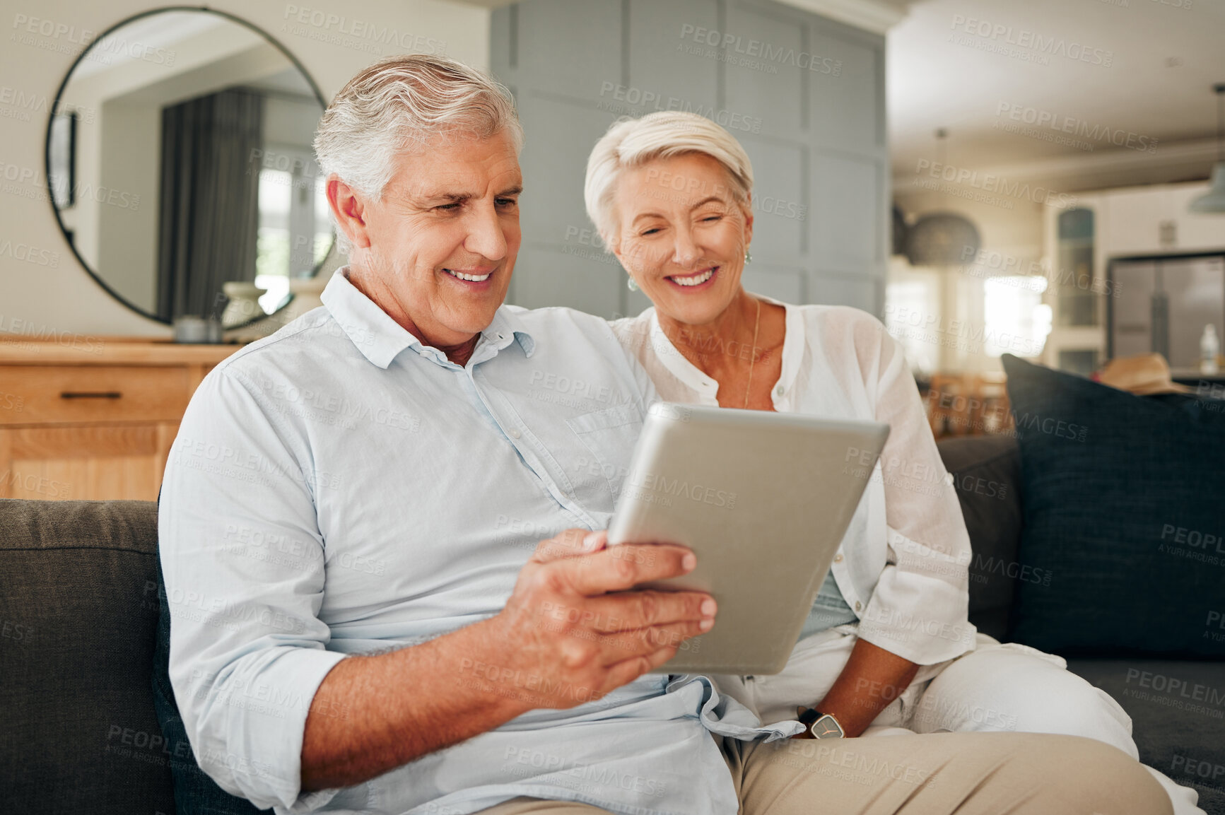 Buy stock photo Senior couple, tablet and smiling while watching video, doing video call or browsing social media sitting on sofa in lounge at home. Happy old man and woman streaming online in their Australia house