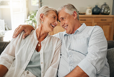 Buy stock photo Couple, love and smile with a senior man and woman sitting face to face on a sofa in the living room of their home. Retirement, happy and romance with an elderly male and female pensioner in a house
