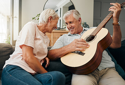 Buy stock photo Senior man and woman with guitar on the sofa at home, enjoying retirement. Old couple playing music on instrument, having fun and laughing together. Elderly husband plays love tune or song for wife