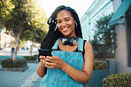 A black woman in the city, in conversation on her smartphone with friends and listening to music on headphones. Walking the street, urban black girl smiling and using 5g connection for communication 