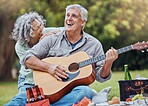 Elderly, couple and guitar at happy picnic in garden, park or nature together. Man, woman and music for happiness on travel to countryside for lunch, food or relax with love by trees in sunshine