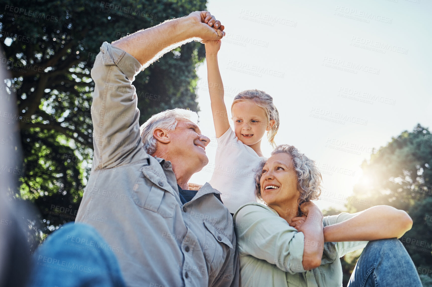 Buy stock photo Grandparents playing together with a girl in the park in the morning. Family, love and grandchild bonding with grandmother and grandmother in a garden. Child holding hands with senior couple outside