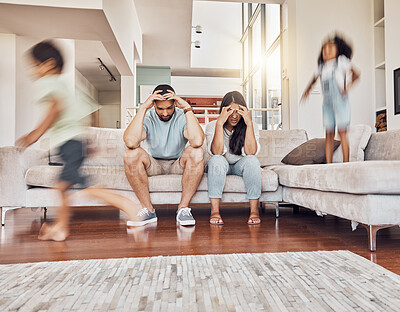 Buy stock photo Stress, headache and family with children running in living room with parents on sofa with fatigue, mental health or tired. Crazy, noise and youth with kids playing with frustrated mother and father 