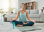 Meditation, fitness and headphones with woman in living room listening to podcast, audio or music to relax. Wellness, peace and zen with girl and yoga in home gym for health, sports and workout