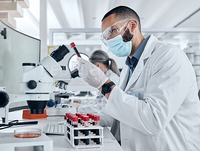 Buy stock photo Scientist doing research for covid using a microscope and test tube in a lab. Healthcare worker in biotechnology, medicine and analytics testing liquid in science laboratory for blood sample results