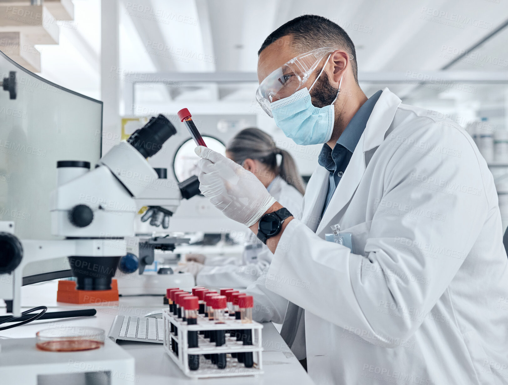 Buy stock photo Scientist doing research for covid using a microscope and test tube in a lab. Healthcare worker in biotechnology, medicine and analytics testing liquid in science laboratory for blood sample results