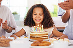 Little girl, birthday and candle cake for wish in party celebration for child in happiness at home. Happy kid with smile sitting by candles for event or special day celebrating with her parents