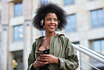 Young african american woman wearing headphones listening to music using smartphone in city
