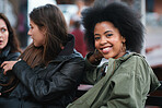African american woman with afro hanging out with friends sitting on bench in city smiling enjoying socializing 