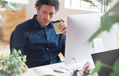 Businessman writing in notebook journal brainstorming ideas holding coffee sitting at desk in office