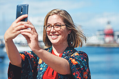 Buy stock photo Happy travel woman taking selfie photo using smartphone camera in waterfront harbour sharing vacation holding mobile phone