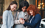 Beautiful business women using smartphone girl friends browsing mobile phone enjoying gossip in city