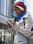 Muslim business woman using smartphone listening to music with headphones in city independent female wearing hijab headscarf
