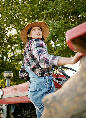 Buy stock photo Woman agriculture worker or farmer on tractor working farm during harvest time. Sustainability farming in the countryside. Serious girl farming in a field, fresh produce for farmers market