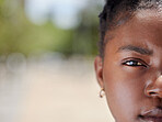 Serious face portrait of a woman with clear skin outdoors in natural light and background. African, female eye and head zoom focus isolated in nature with a confident and vision empowerment look