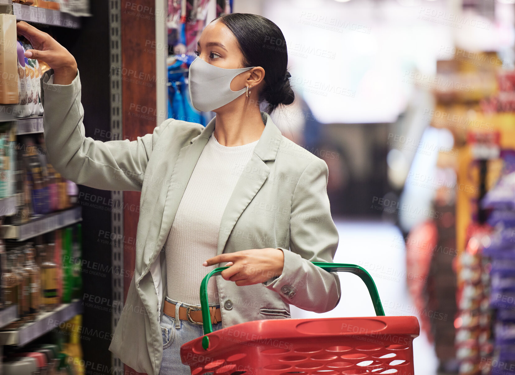 Buy stock photo Supermarket, shopping and customer with covid face mask in retail store for food, groceries or product from shelf. Young woman with basket during inflation price increase or sales choice on grocery