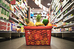 Supermarket, market or grocery store aisle with basket of quality choice, healthy fruits and vegetables. Buying retail sale items in a shopping cart. Group of consumables or food products on floor