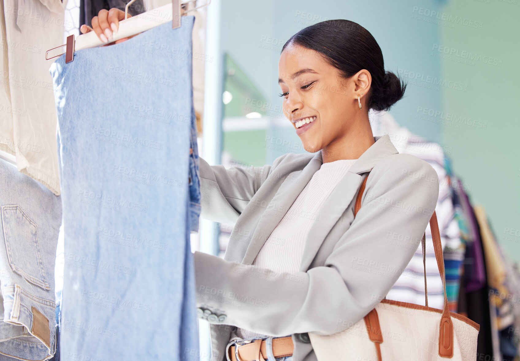 Buy stock photo Shopping, fashion and woman alone in a retail clothing store for weekend clothes at the market. Female happy shopper with smile looking at stylish denim pants and feeling material, quality and style.