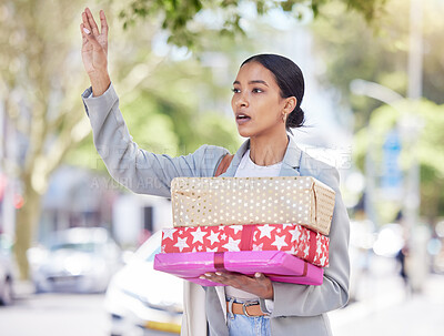 Buy stock photo Woman holding gift and calling for a taxi in the street for travel to a birthday, anniversary or congratulation party. City girl standing in the road after shopping for a present for friend or family