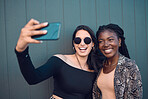 Happy girl friends taking a selfie on phone while traveling around the city on summer vacation. Diversity, love and smiling women taking picture on smartphone to post on social media and the internet