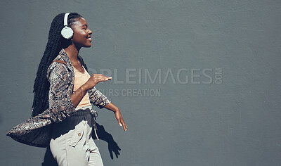 Buy stock photo Music, university and college dance student dancing and listening to podcast or radio on headphone walking past campus. Copy space banner for education mock up content on grey wall background.