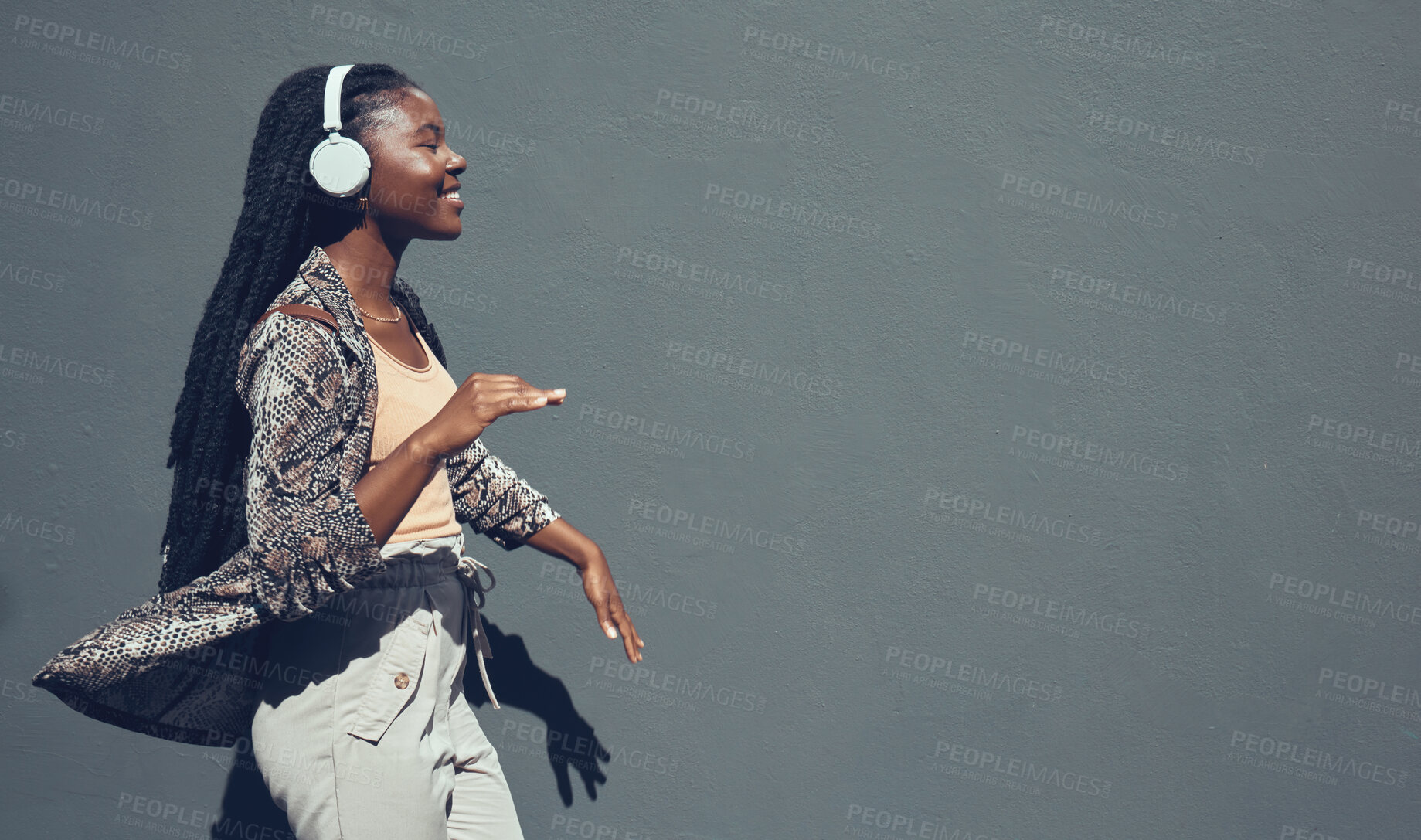 Buy stock photo Music, university and college dance student dancing and listening to podcast or radio on headphone walking past campus. Copy space banner for education mock up content on grey wall background.