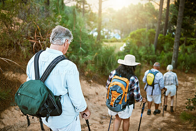 Buy stock photo Hiking, adventure and exploring with a group of senior friends walking on a trail in the forest or woods. Rearview of retired people taking a hike or journey on a discovery vacation outdoors
