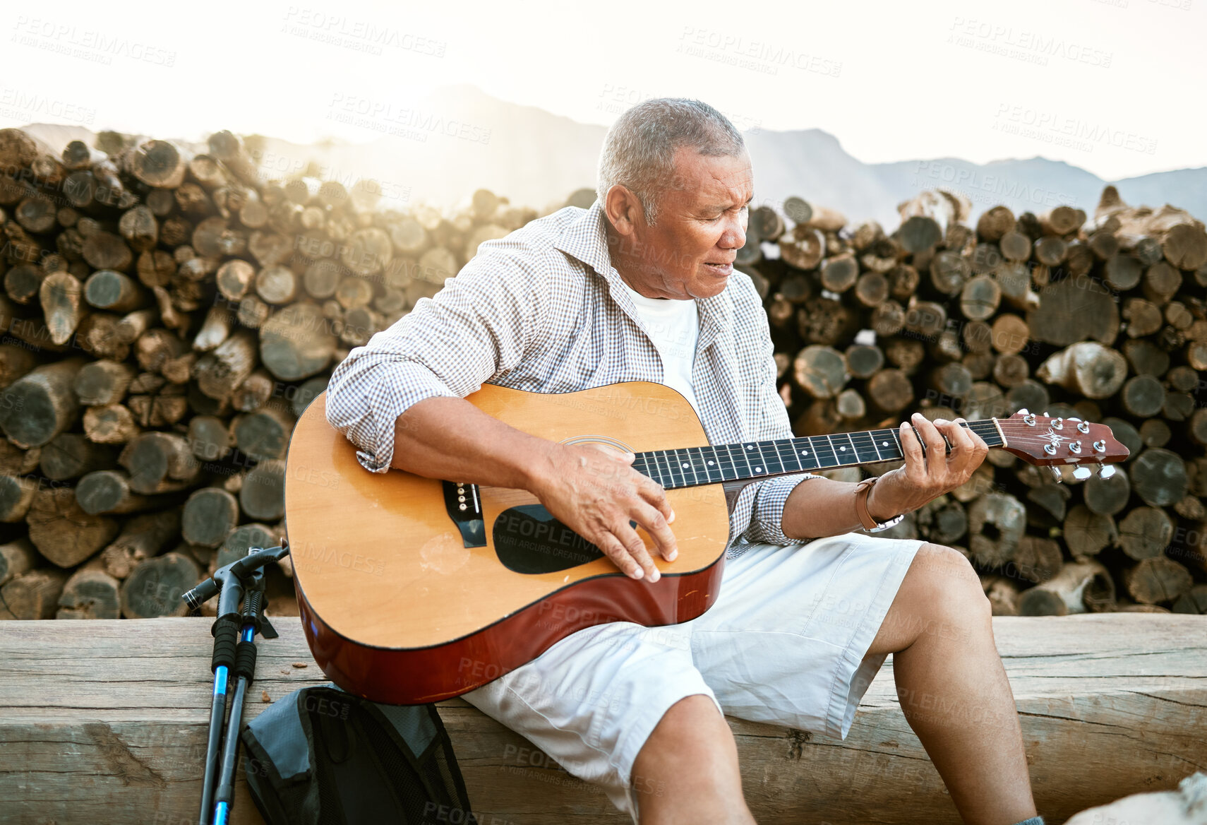 Buy stock photo Mature man, relaxing and playing the guitar while sitting outdoors and enjoying his hobby while getting fresh air. Older man singing a song in his free time in retirement with a musical instrument