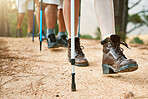 Group of hikers hiking with walking sticks on a trail outdoors in nature for fitness. Fit, active and sporty people on an adventure. Adult friends taking a stroll for exercise and health.