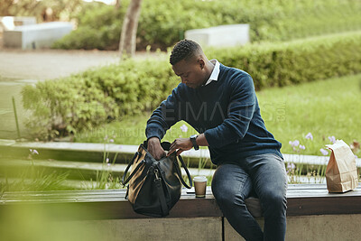 Buy stock photo Businessman city park, food and lunch break with coffee or tea drink in paperbag. Young African entrepreneur looking in bag for strategy notebook and sitting outside in urban environment alone