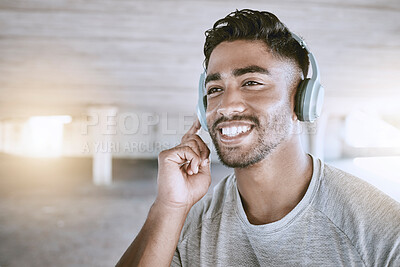Buy stock photo Workout music, fitness headphones or digital radio. Music technology device plays music, smiling relaxed indian man listening to audio sound earphone while exercising in city parking lot closeup.