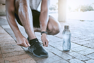 Shoes, water bottle and hand of runner for motivation and in fitness training in city street. Start workout exercise for sport run on road in town. Running athlete foot prepare for wellness and sport